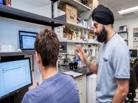 Dr. Taran Gujral (standing) and postdoctoral research fellow Dr. Thomas Bello discuss their research in July 2019.