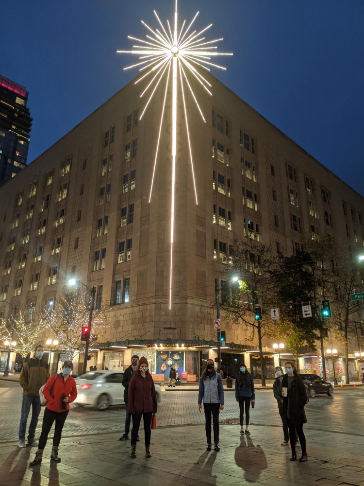 Group stands in front of a holiday star in downtown Seattle