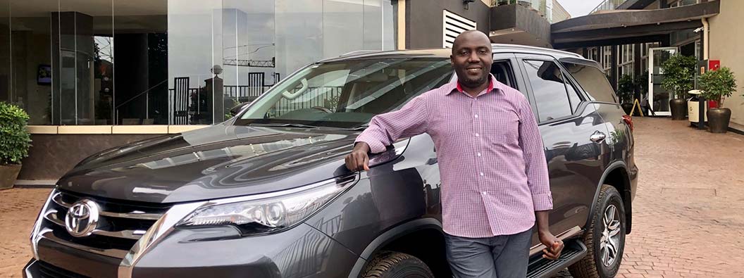 Isma Lubega, the driver for the Collaboration, stands by the program's car